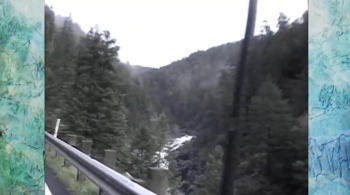 A blurry photo of the view outside a car window looking over some trees and a river by the side of the road. On either side of the footage is a green-blue sidebar with edited textures over it.